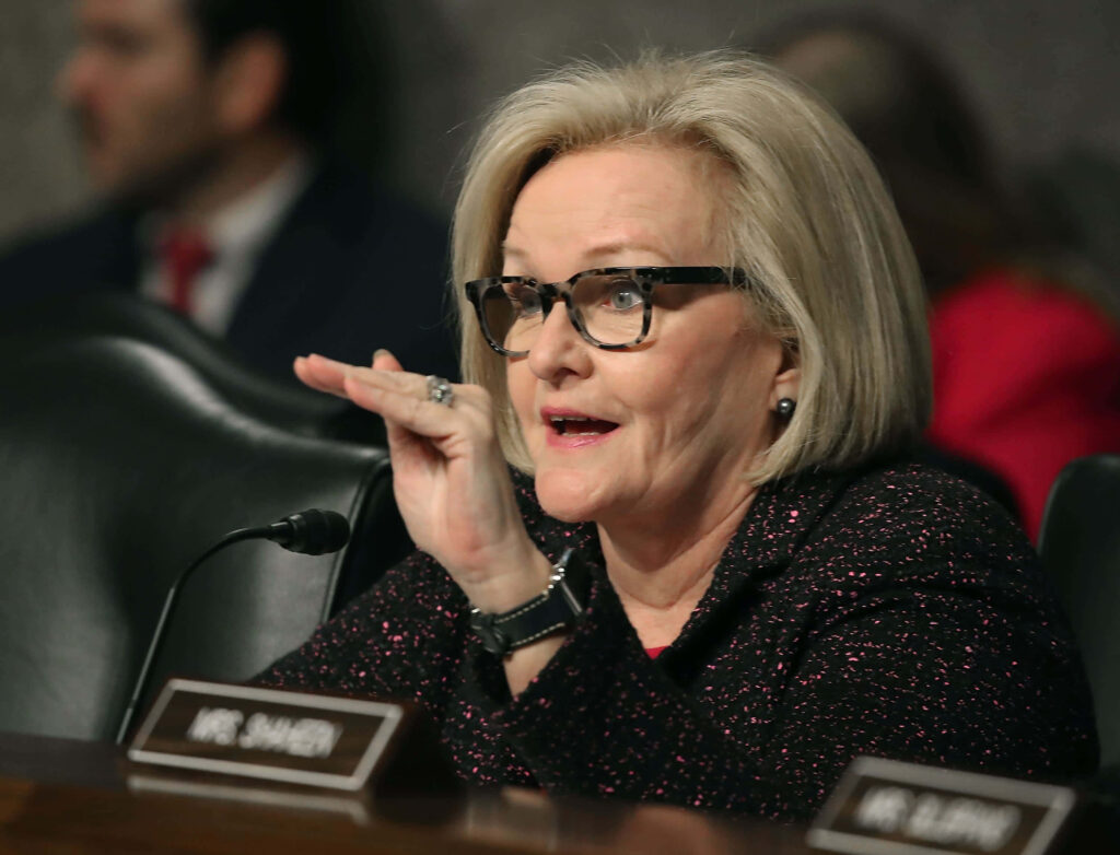 Claire McCaskill engaged in serious discussion with witness in formal setting professional attire wallpaper background