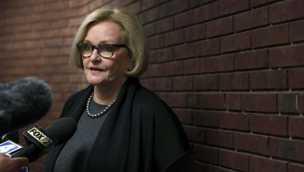 Claire McCaskill speaks at press conference against brick wall with multiple news microphones Wallpaper