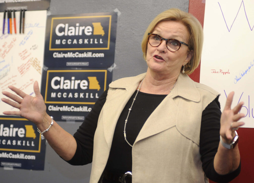 Claire McCaskill speaking at election event with campaign posters in professional attire wallpaper background