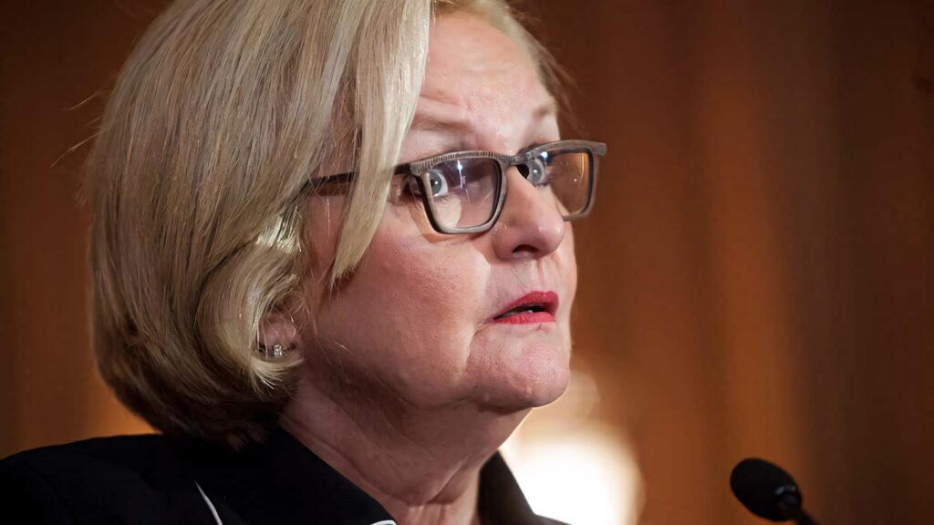 Claire McCaskill speaking with focused expression sharp glasses professional attire wallpaper background