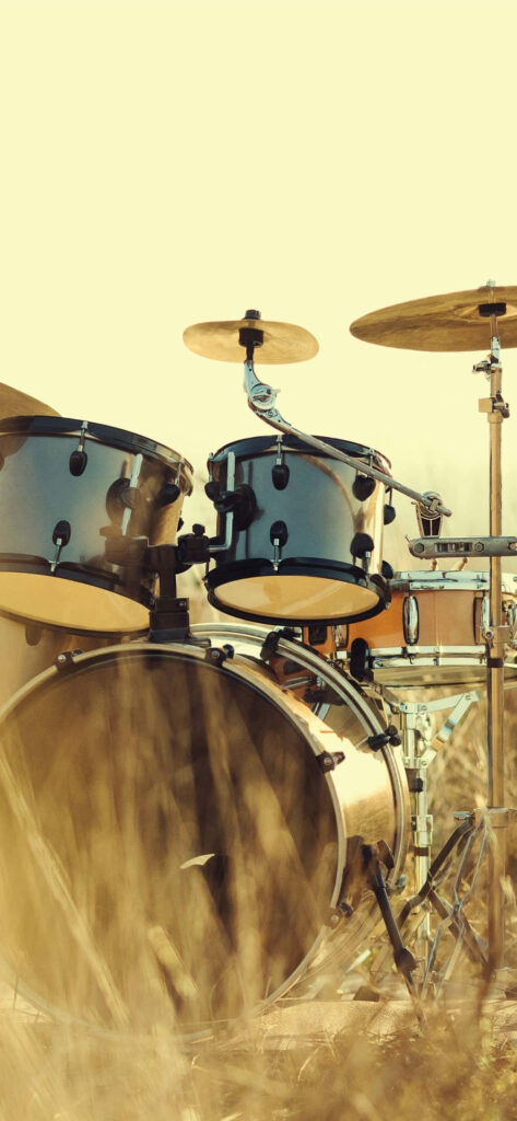 Classic acoustic drum set outdoors in warm light with wooden metal textures on yellow background Wallpaper