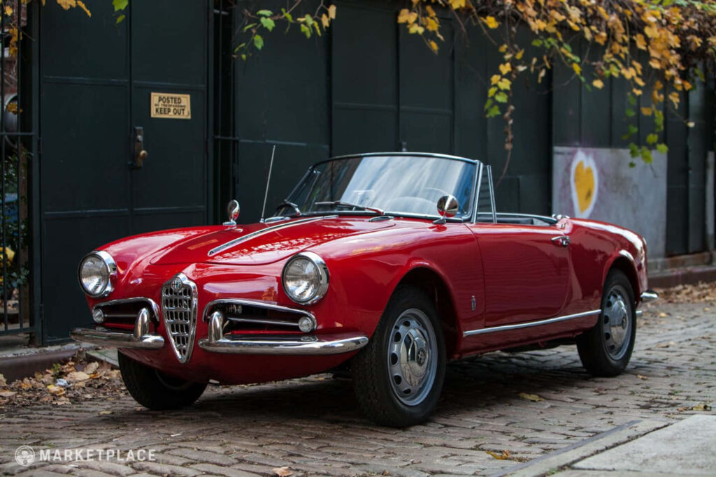 Alfa Romeo Spider vintage car on cobblestone street with autumn leaves classic Italian design Wallpaper