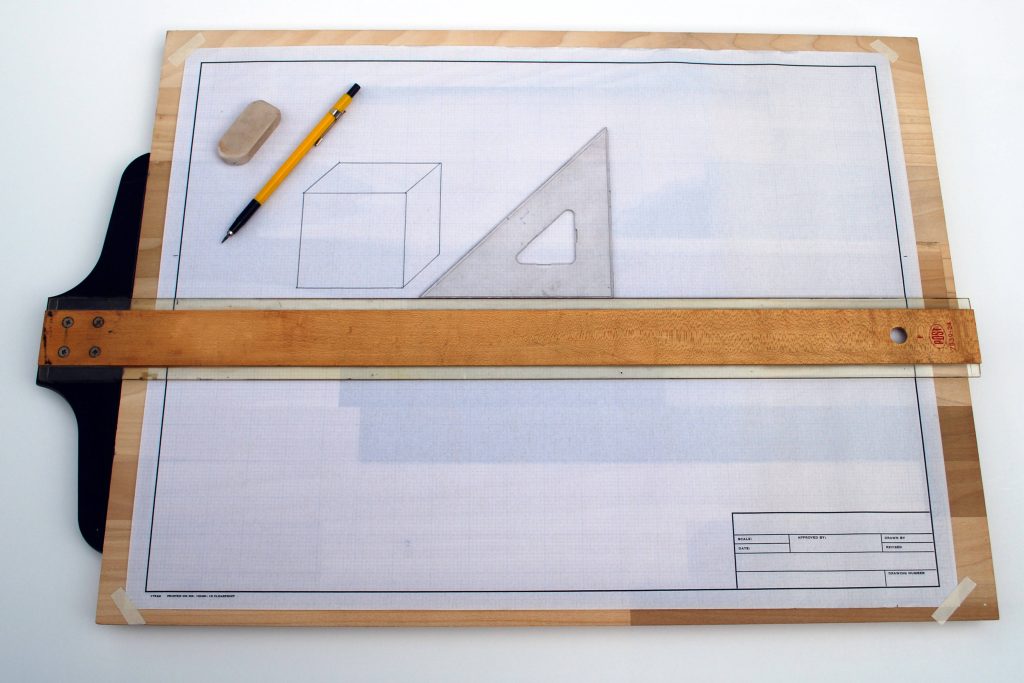 High-angle photo of classic architectural drafting setup with wooden T-square and hand-drawn cube Wallpaper