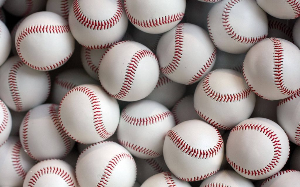 Close-up of classic white leather baseballs with red stitching dense pile wallpaper background