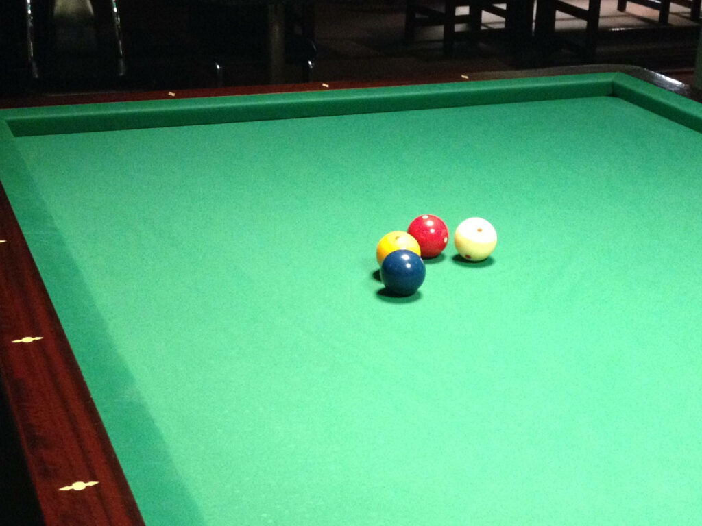 Four colorful billiard balls clustered on green pool table classic focused wallpaper background