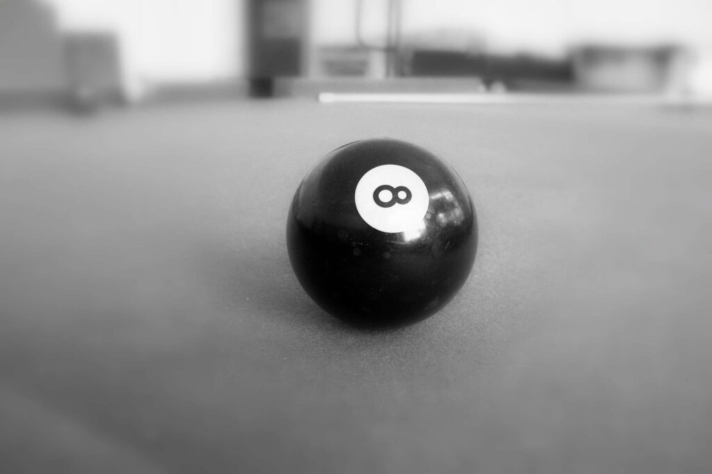 Black eight-ball on blurred billiards table with minimalistic monochrome design wallpaper background