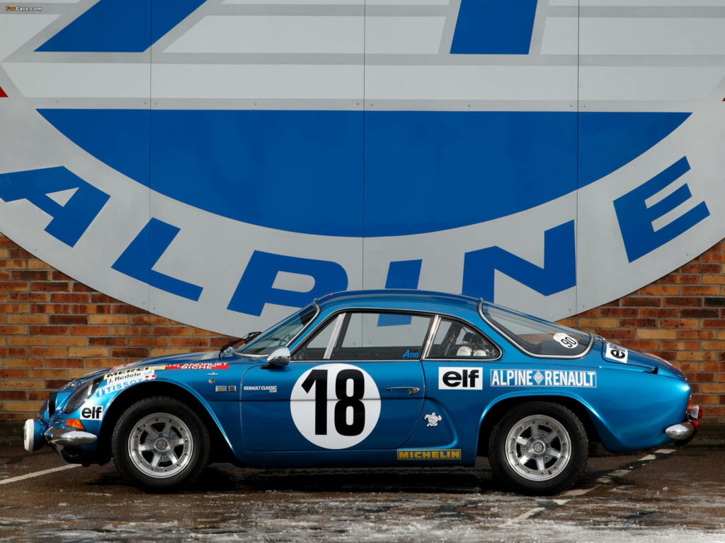 Classic blue Alpine race car number 18 with vintage decals against Alpine logo brick wall background Wallpaper