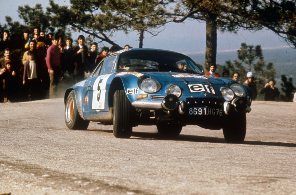 Classic blue Alpine rally car racing dusty road vintage motorsport with roadside spectators Wallpaper