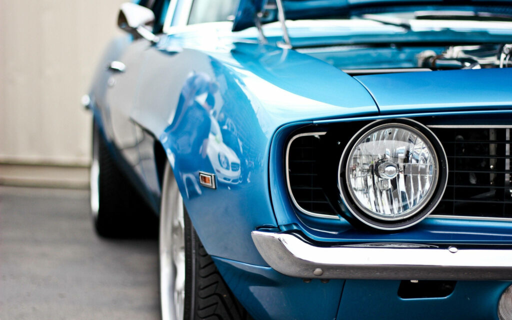 Close-up of classic blue Chevrolet Camaro SS muscle car with iconic headlight and sleek lines Wallpaper