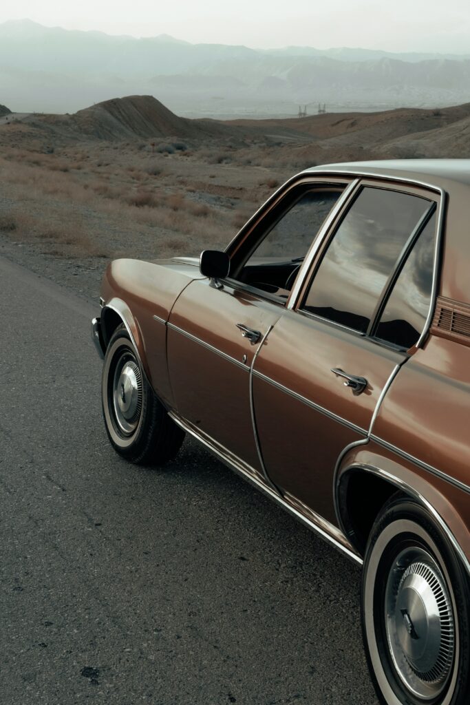 Vintage Brown Retro Car on Scenic Mountain Road Wallpaper