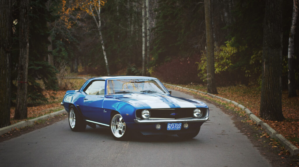 Classic Chevrolet Camaro in Autumn Woods - Sleek Side View Wallpaper