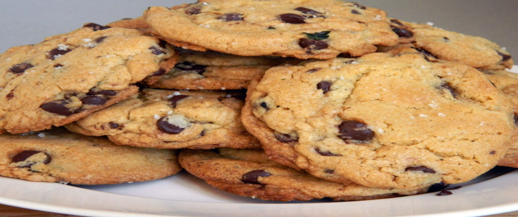 Close-up of homemade chocolate chip cookies with golden edges and melty chocolate chips on plate Wallpaper
