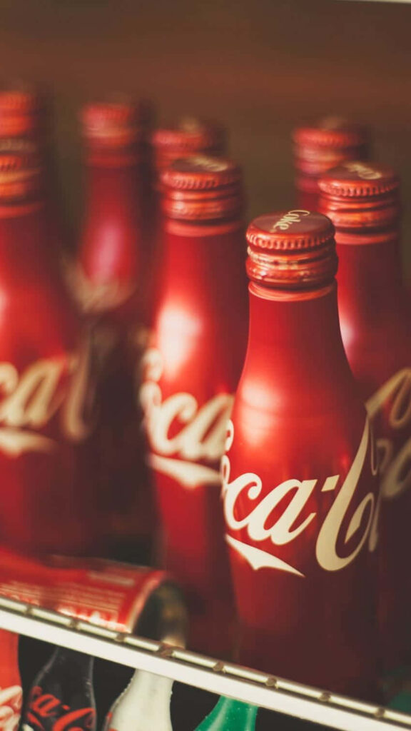 Coca-Cola wallpaper with rows of classic red bottles in vintage cooler warm nostalgic tones