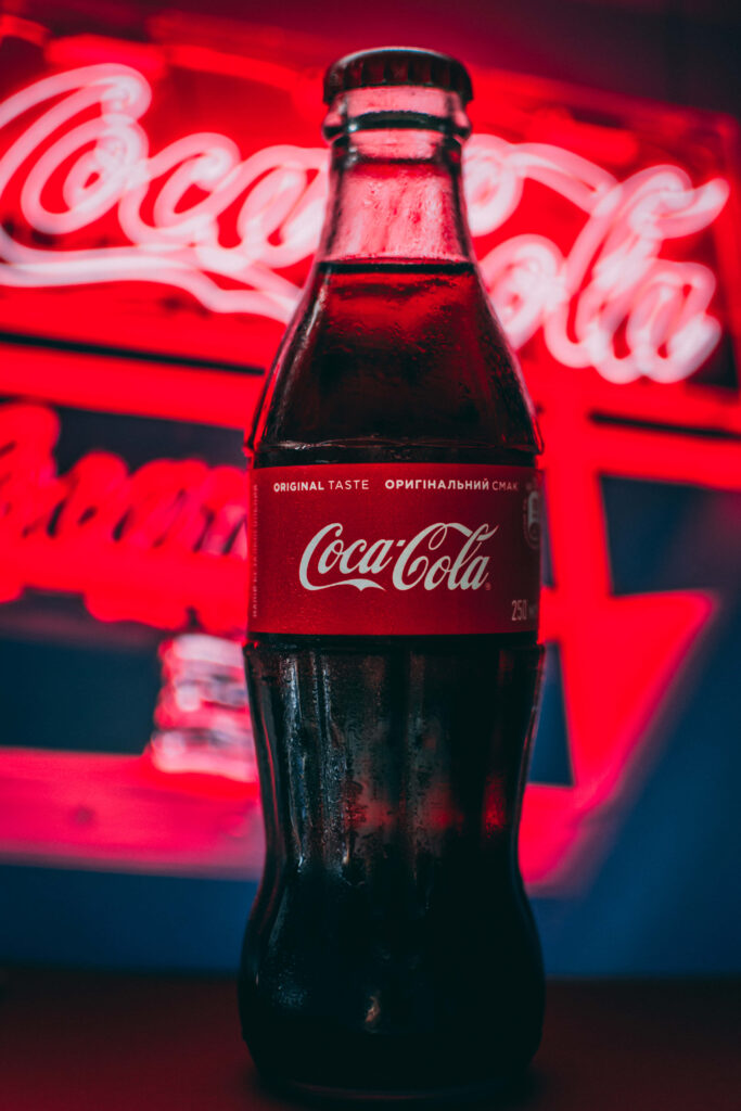 Classic Coca-Cola glass bottle with glowing red neon background highlighting iconic logo Wallpaper