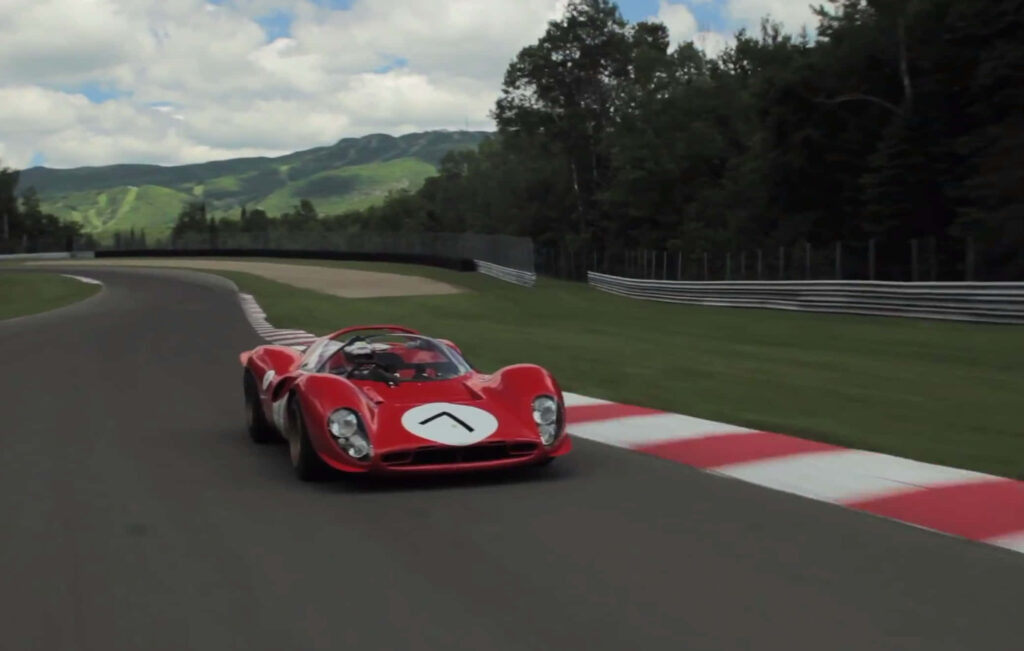 Classic Ferrari 330 racing on winding track with lush greenery and mountains under cloudy sky Wallpaper