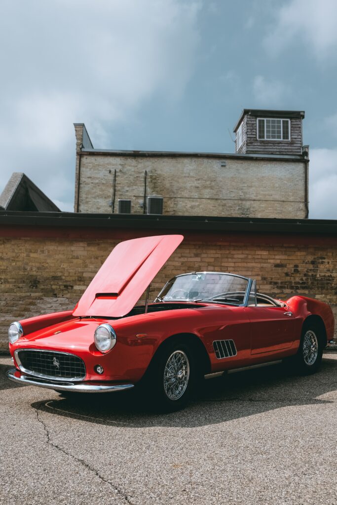 Vibrant Red Ferrari Convertible Against Rustic Brick Background Wallpaper