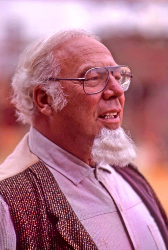 Portrait of legendary actor George Kennedy in profile with white beard glasses textured vest Wallpaper