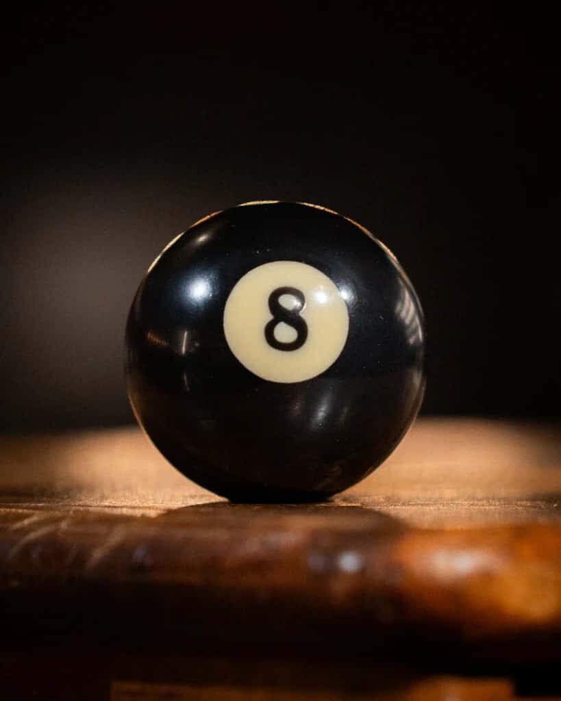 Glossy black eight-ball billiards wallpaper with blurred warm background for pool enthusiasts