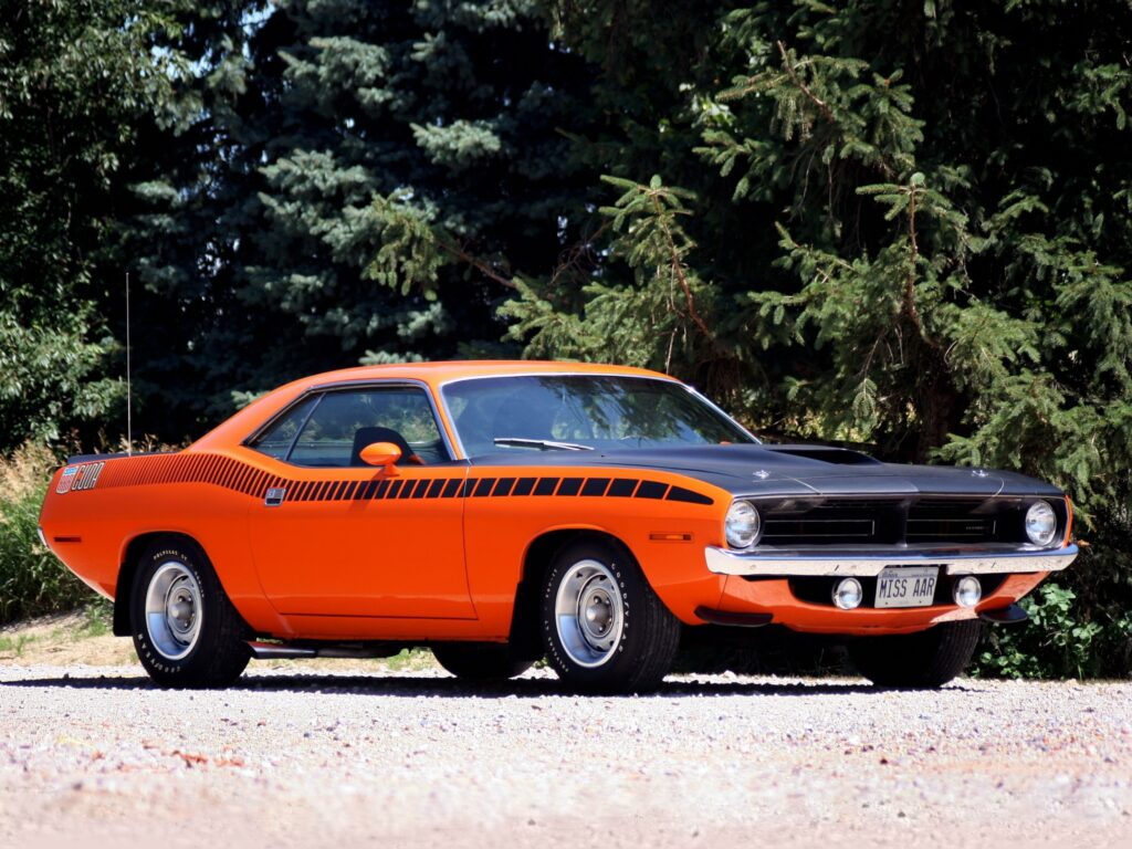 Classic Orange Plymouth Barracuda Wallpaper Amidst Lush Greenery