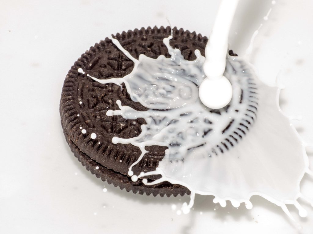 Close-up of classic Oreo cookie splashing into fresh milk high-contrast wallpaper background