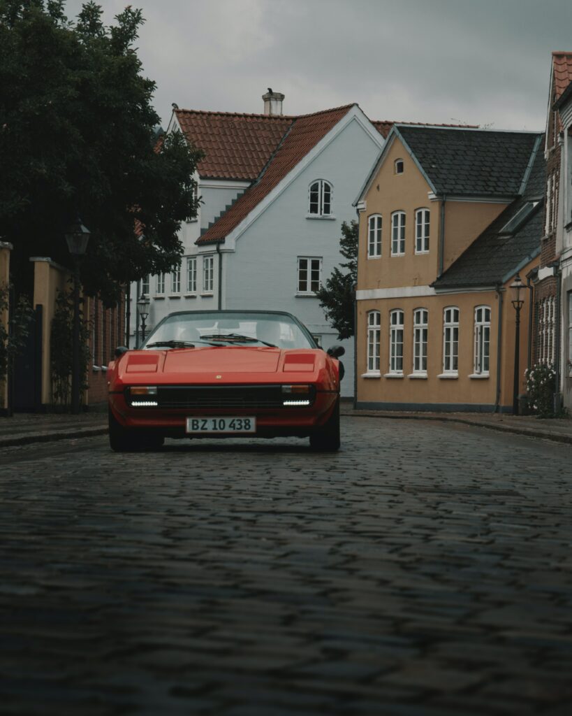Classic Red Ferrari on Cobblestone Street with Historic Architecture Wallpaper