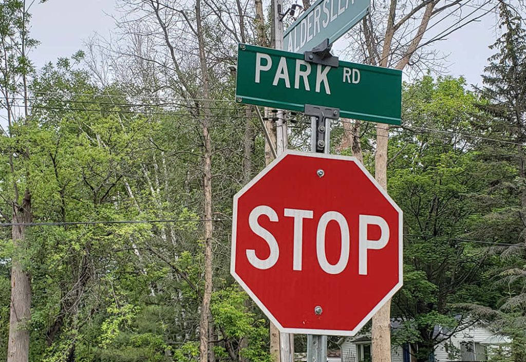 Red octagonal stop sign below green Park Rd street sign with green trees in daylight background Wallpaper