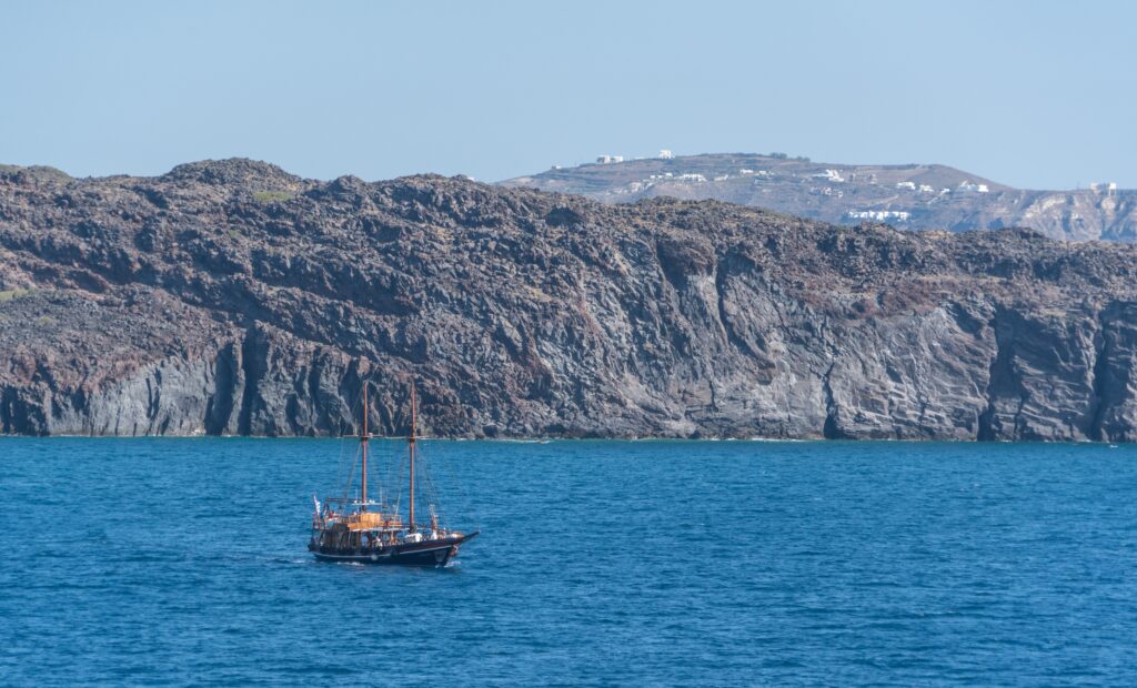 Classic ship sailing on deep blue sea near rugged sunlit cliff coastal adventure wallpaper background