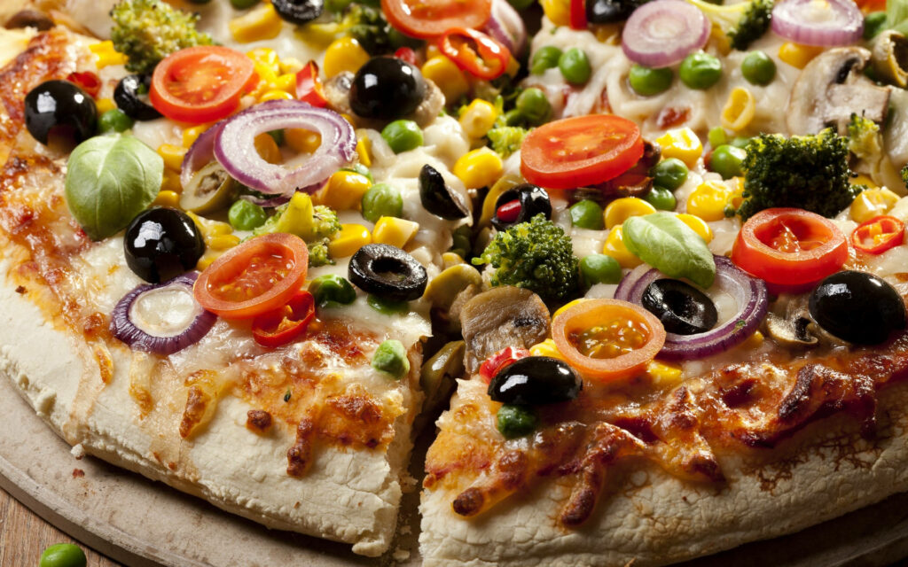 Classic vegan pizza with fresh tomatoes olives red onions broccoli and basil on golden crust Wallpaper