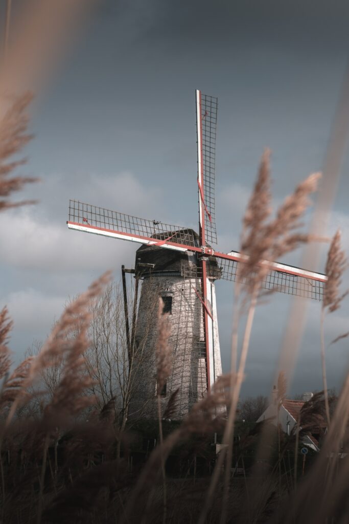 Classic windmill in golden grass field under cloudy sky peaceful rural wallpaper background