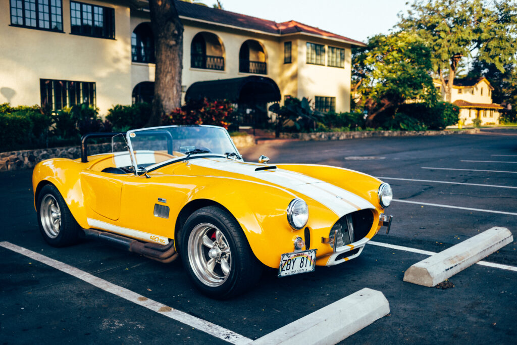 Classic Yellow Retro Car Wallpaper in Sunlit Empty Lot