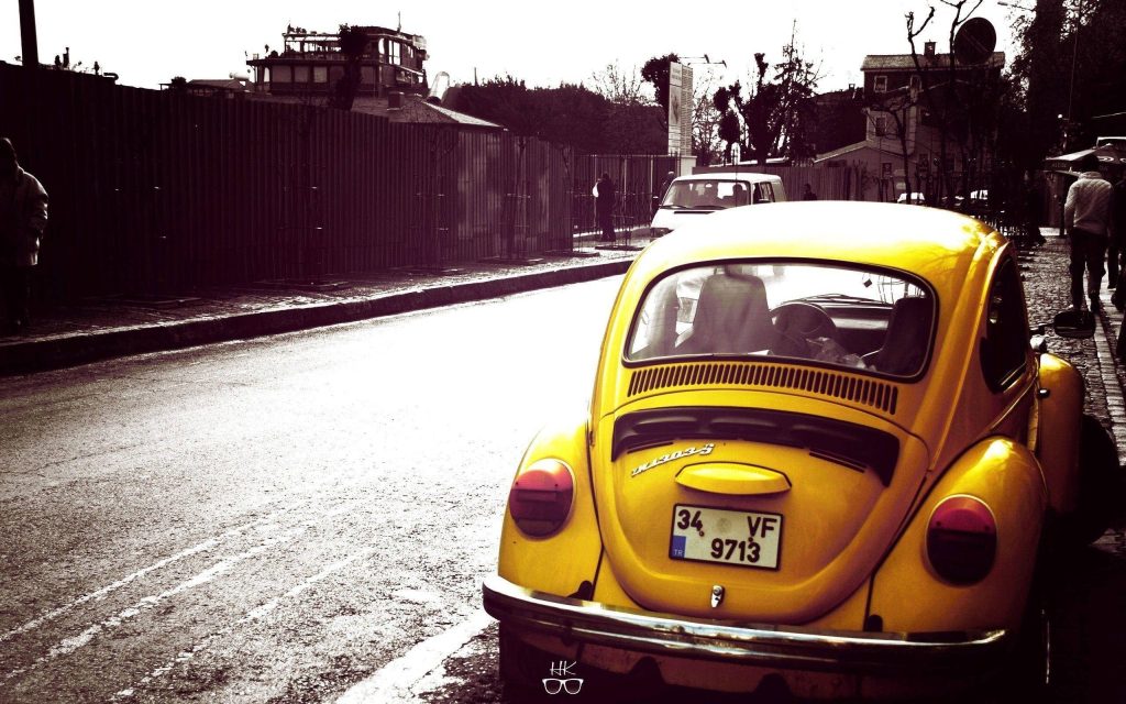 Yellow Volkswagen Beetle rear view on urban street bright classic car wallpaper background