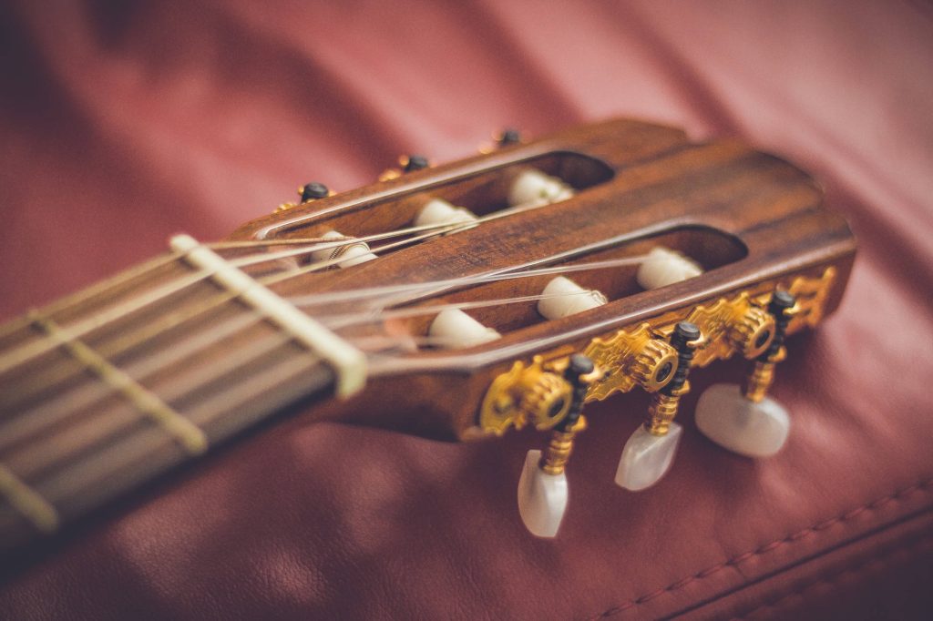 Macro shot of classical guitar headstock with gold tuning pegs and red leather background wallpaper