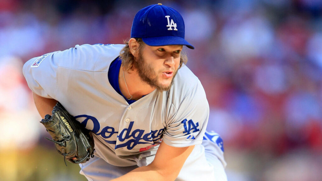 Clayton Kershaw pitching in Dodgers blue uniform with intense focus in stadium background Wallpaper