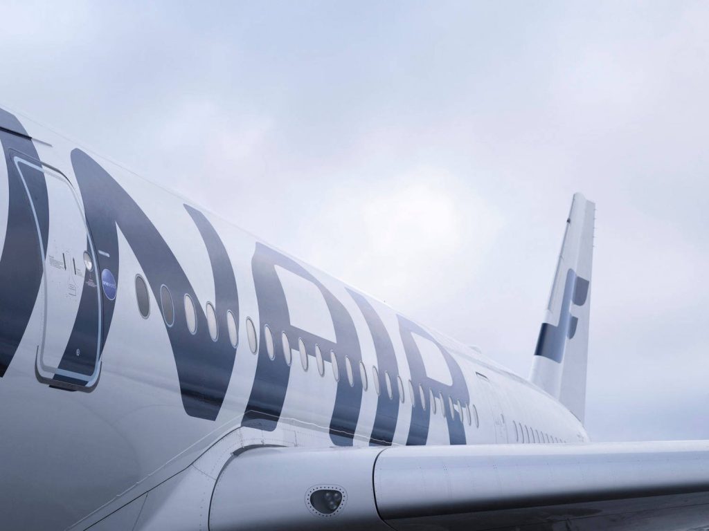 Close-up of Finnair airplane fuselage with overcast sky modern clean aviation wallpaper background