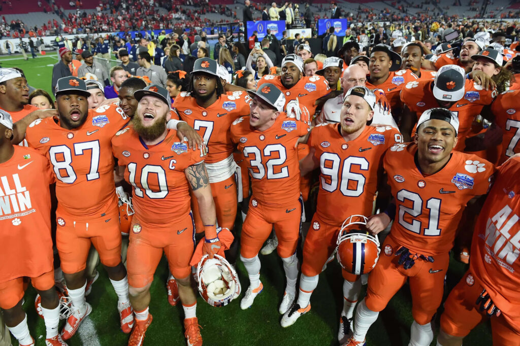Clemson Tigers football team celebrating victory in bright orange uniforms on field wallpaper
