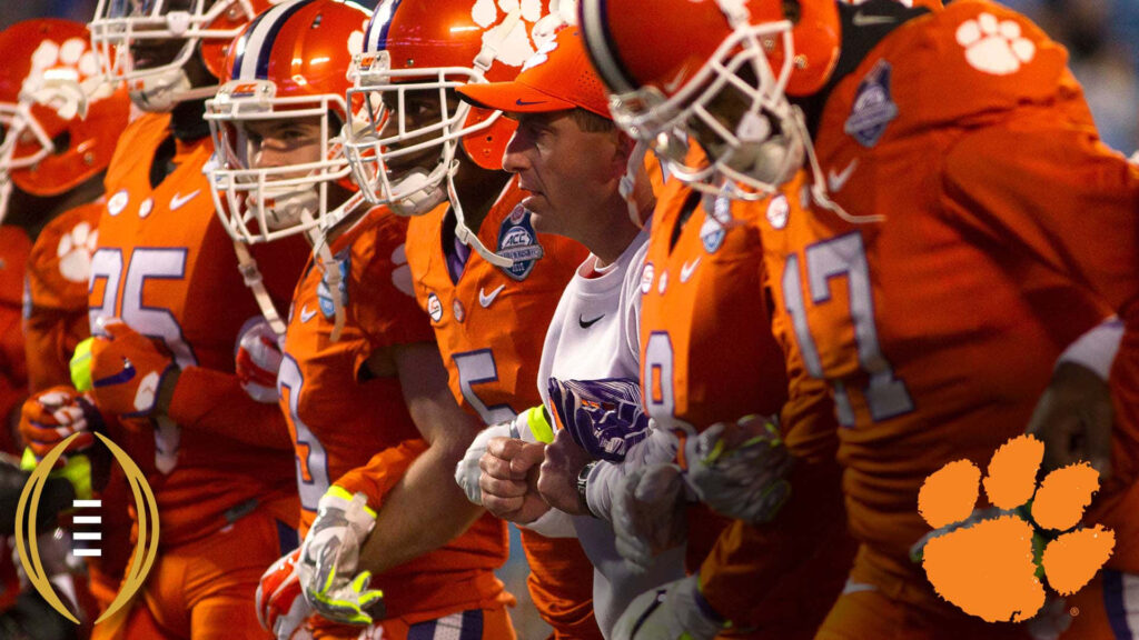 Clemson Tigers football team in orange uniforms and coach united with stadium lights background Wallpaper