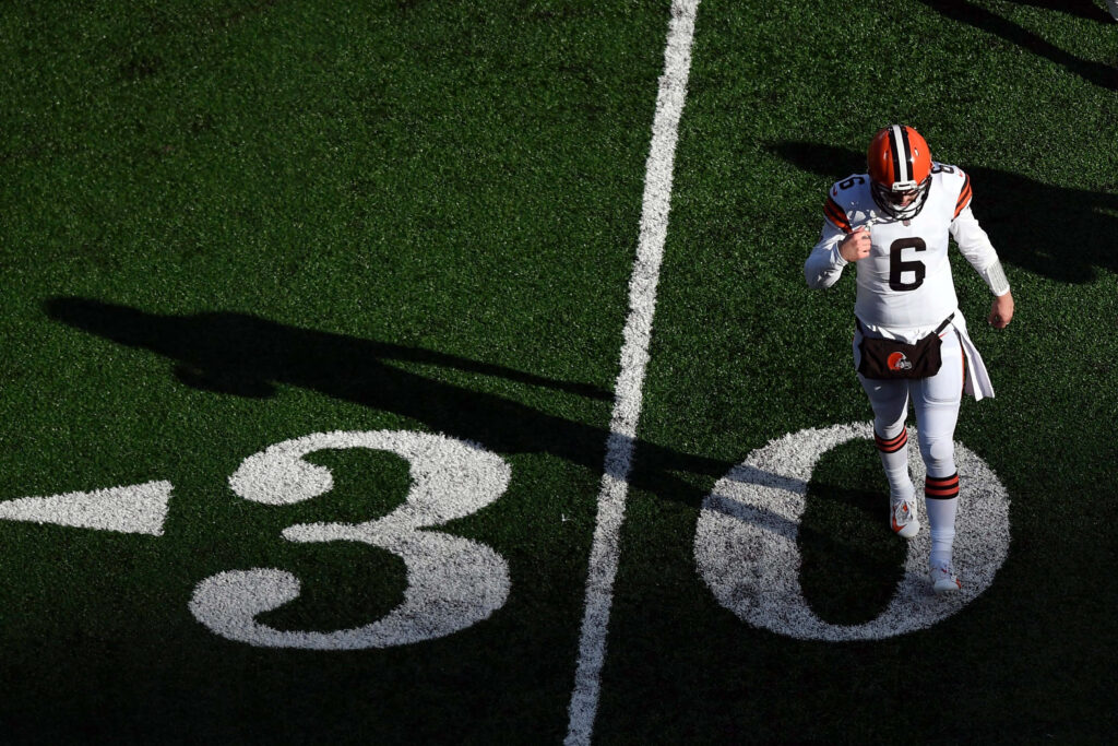 Football player in white Cleveland Browns uniform on sunlit 30-yard line green field overhead view Wallpaper