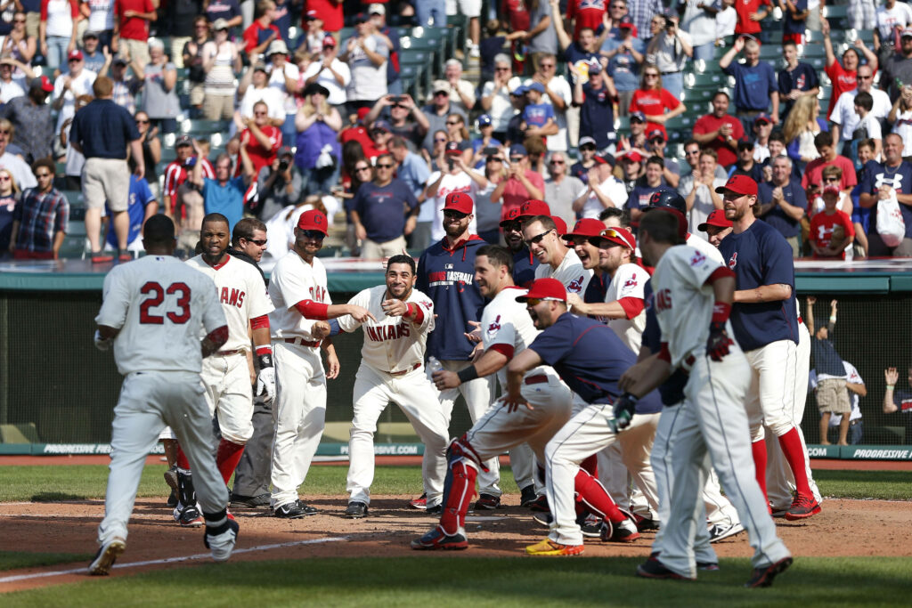 Cleveland Indians players in white uniforms celebrate a home run at home plate with crowd cheers Wallpaper