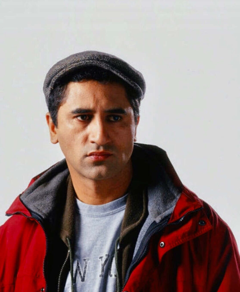 Cliff Curtis wearing flat cap red jacket gray hoodie calm thoughtful expression wallpaper background