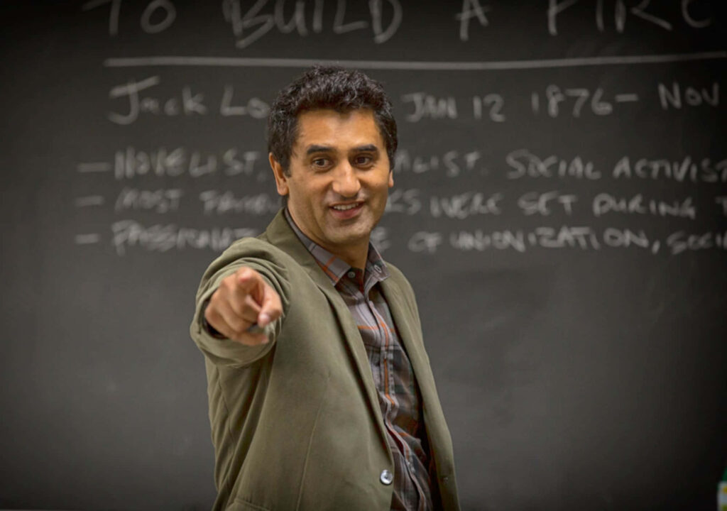 Cliff Curtis pointing at chalkboard with handwritten lesson notes natural classroom lighting Wallpaper