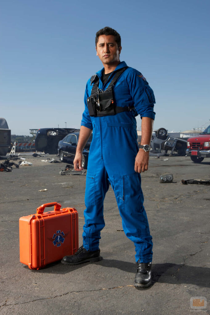 Cliff Curtis in blue rescue uniform standing amid urban disaster with overturned cars high def Wallpaper