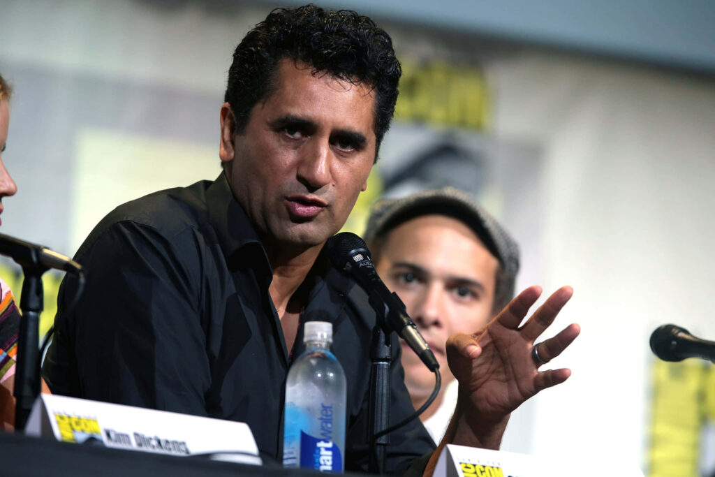Cliff Curtis speaking passionately at panel event with microphone and water bottle on table Wallpaper