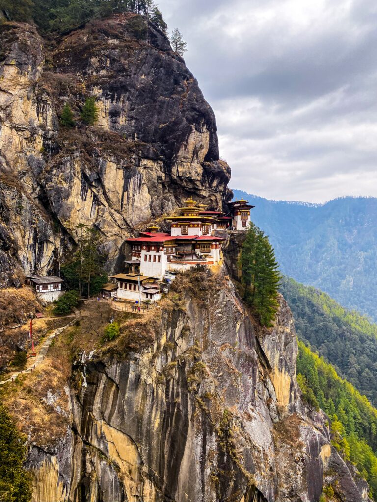 Cliffside pagoda on rugged rocks surrounded by lush forest and towering stone cliffs wallpaper