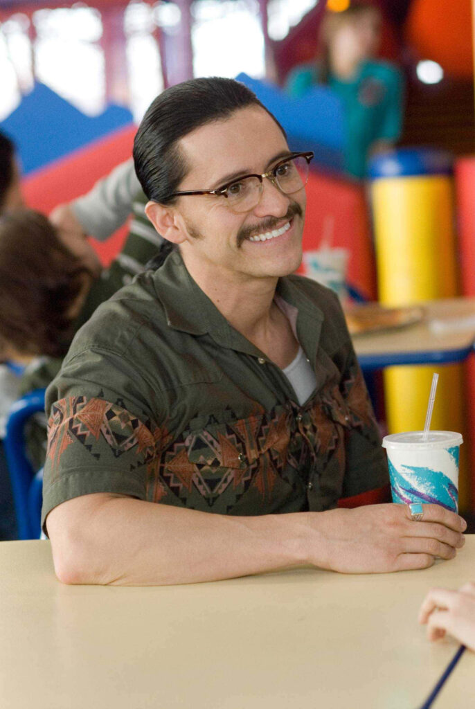 Clifton Collins Jr smiling with drink seated at colorful table wearing patterned shirt and glasses Wallpaper