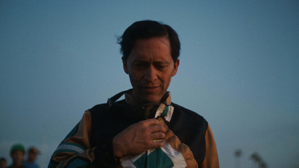 Clifton Collins Jr in soft evening light with earthy tones wearing detailed racing jacket contemplative Wallpaper