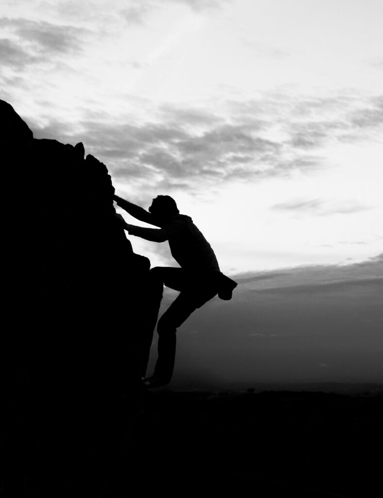Silhouette of Climber: Bold Black and White Rock Face Wallpaper
