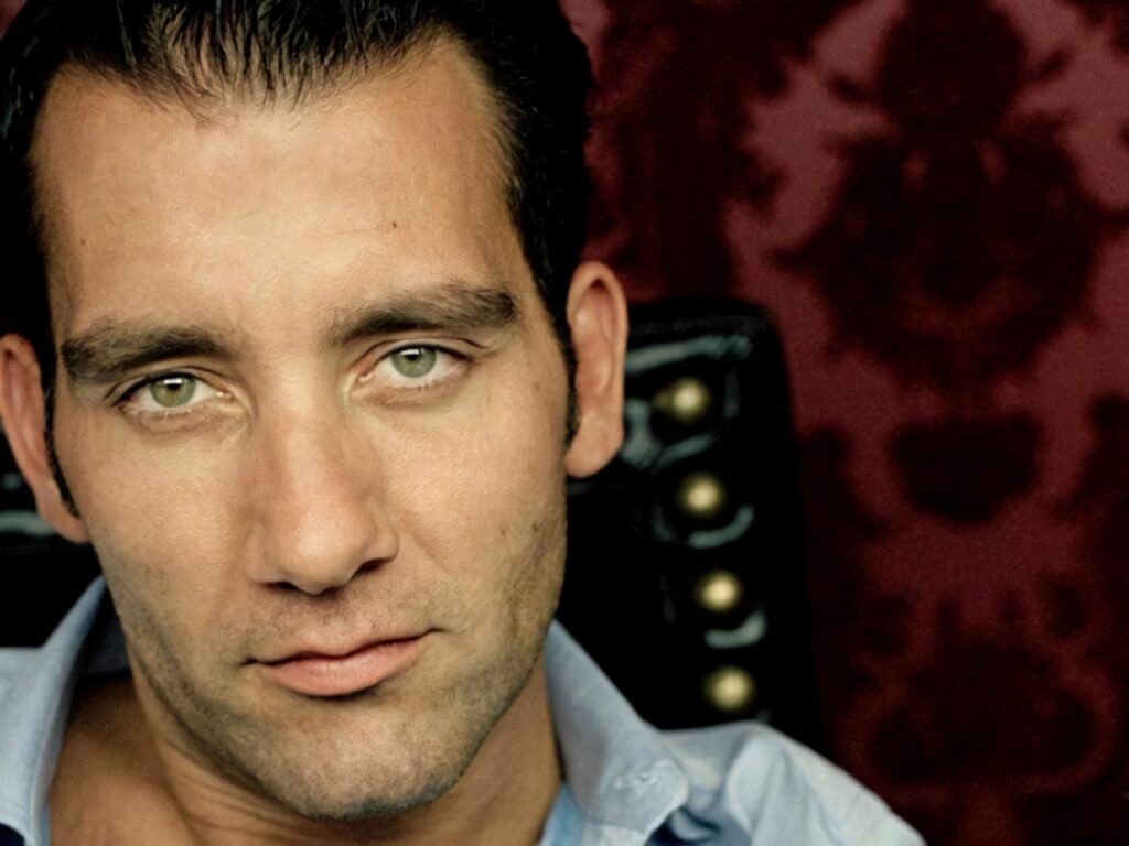 Clive Owen close-up portrait with intense gaze red damask wallpaper background charismatic style
