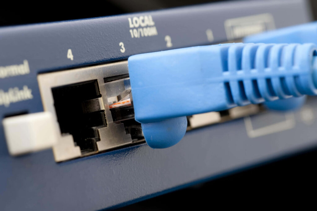 Close-up of blue Ethernet cable connected to network switch showcasing technology and connectivity Wallpaper