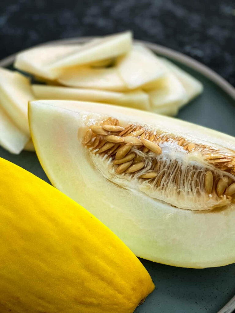 Close up of juicy canary melon with bright yellow rind and textured seeds on dark background Wallpaper