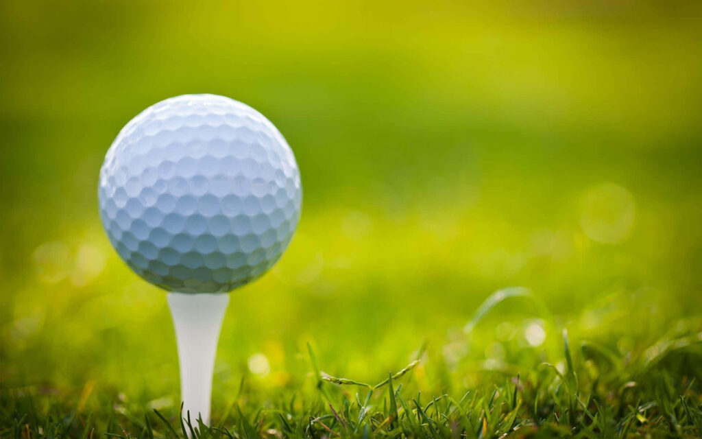 Close-Up Golf Ball on Tee with Lush Green Background Wallpaper
